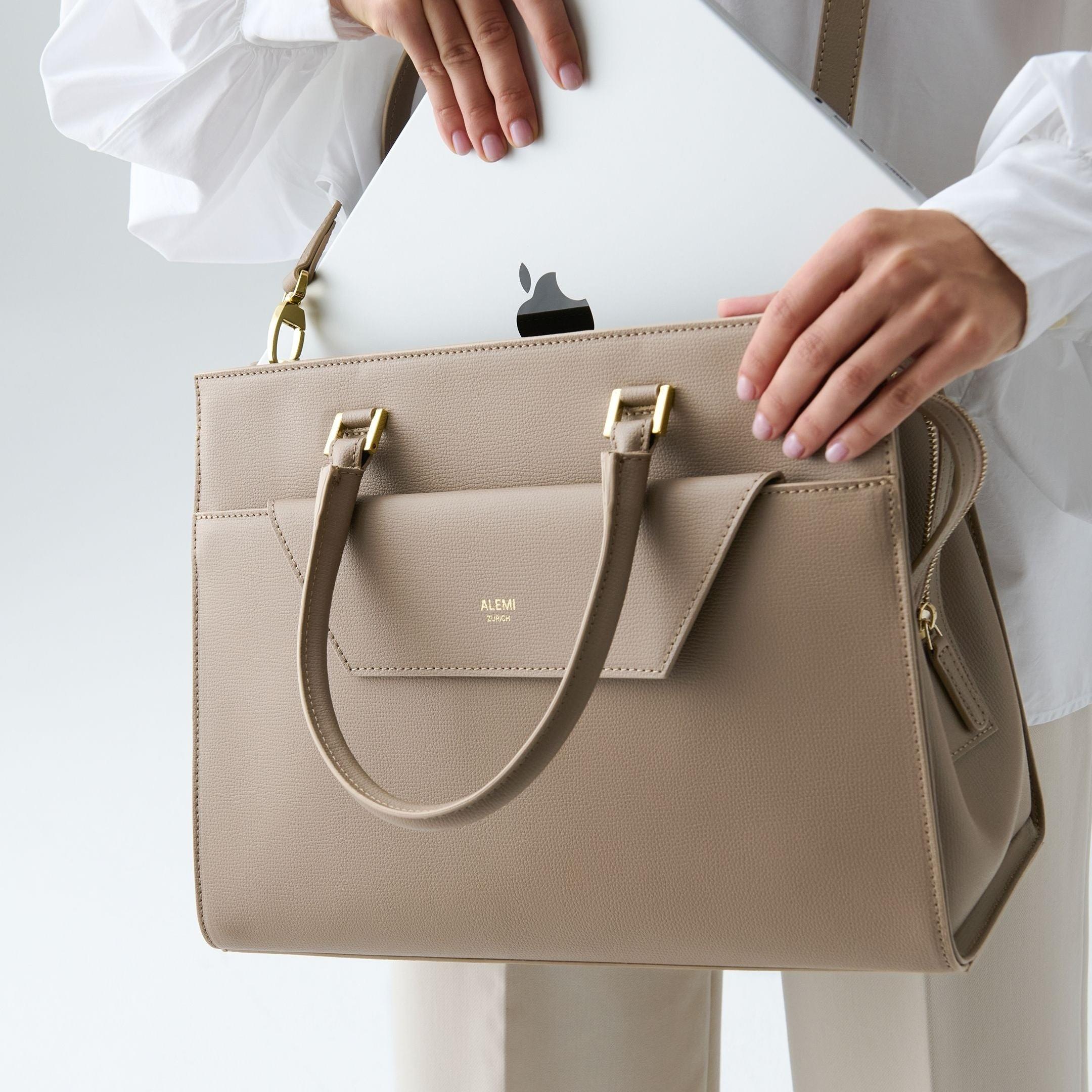 ALEMI Zurich | CENTRAL | Laptop Bag | Greige | Pebbled Leather | Model carrying bag by strap laptop