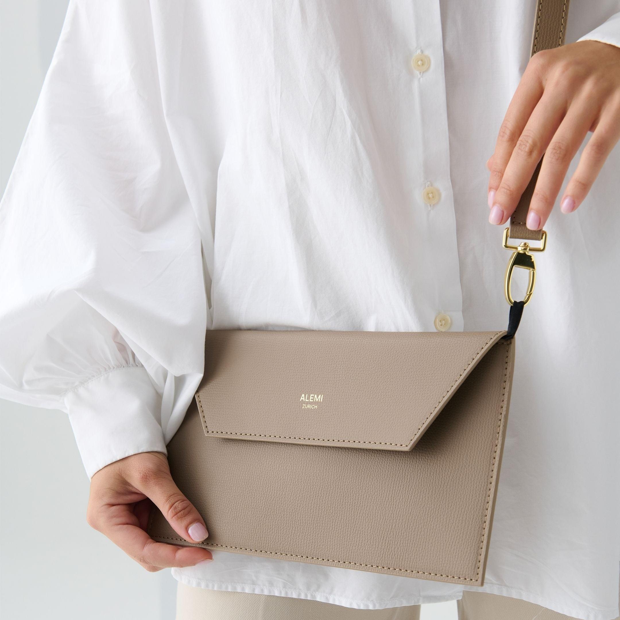 ALEMI Zurich | CENTRAL | Laptop Bag | Greige | Pebbled Leather | Model carrying Clutch by strap