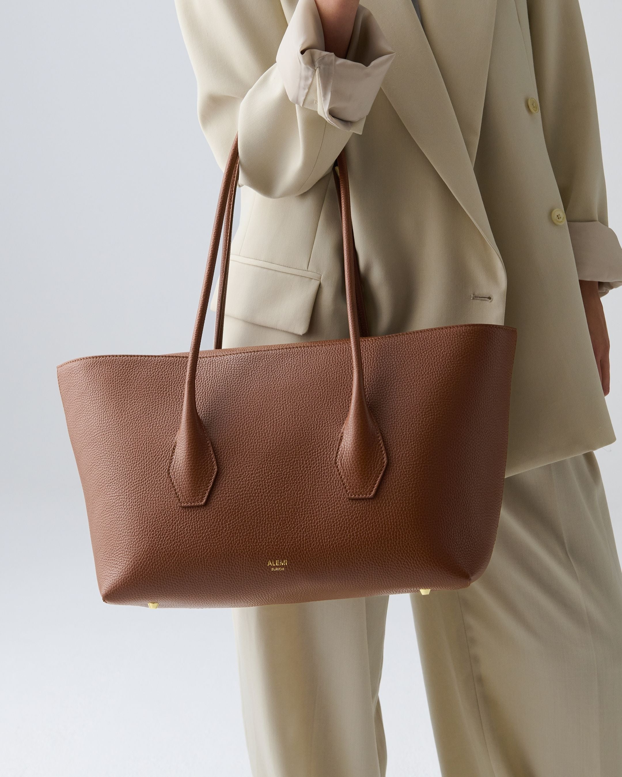 ALEMI Zurich | IDA | Laptop Bag | Cognac | Soft Grain Leather | Model carrying bag by handle close up