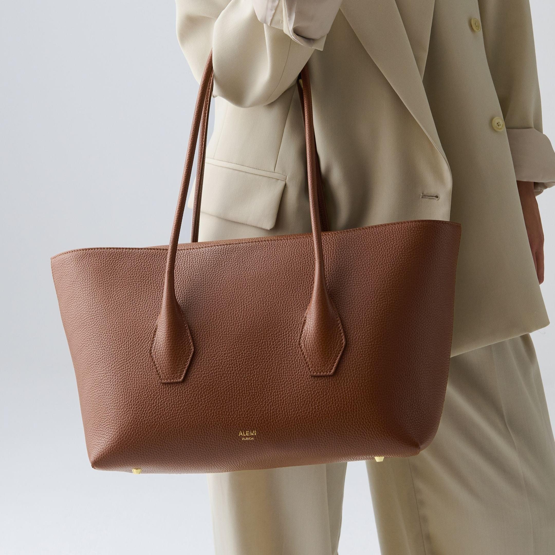 ALEMI Zurich | IDA | Laptop Bag | Cognac | Soft Grain Leather | Model carrying bag by handle close up