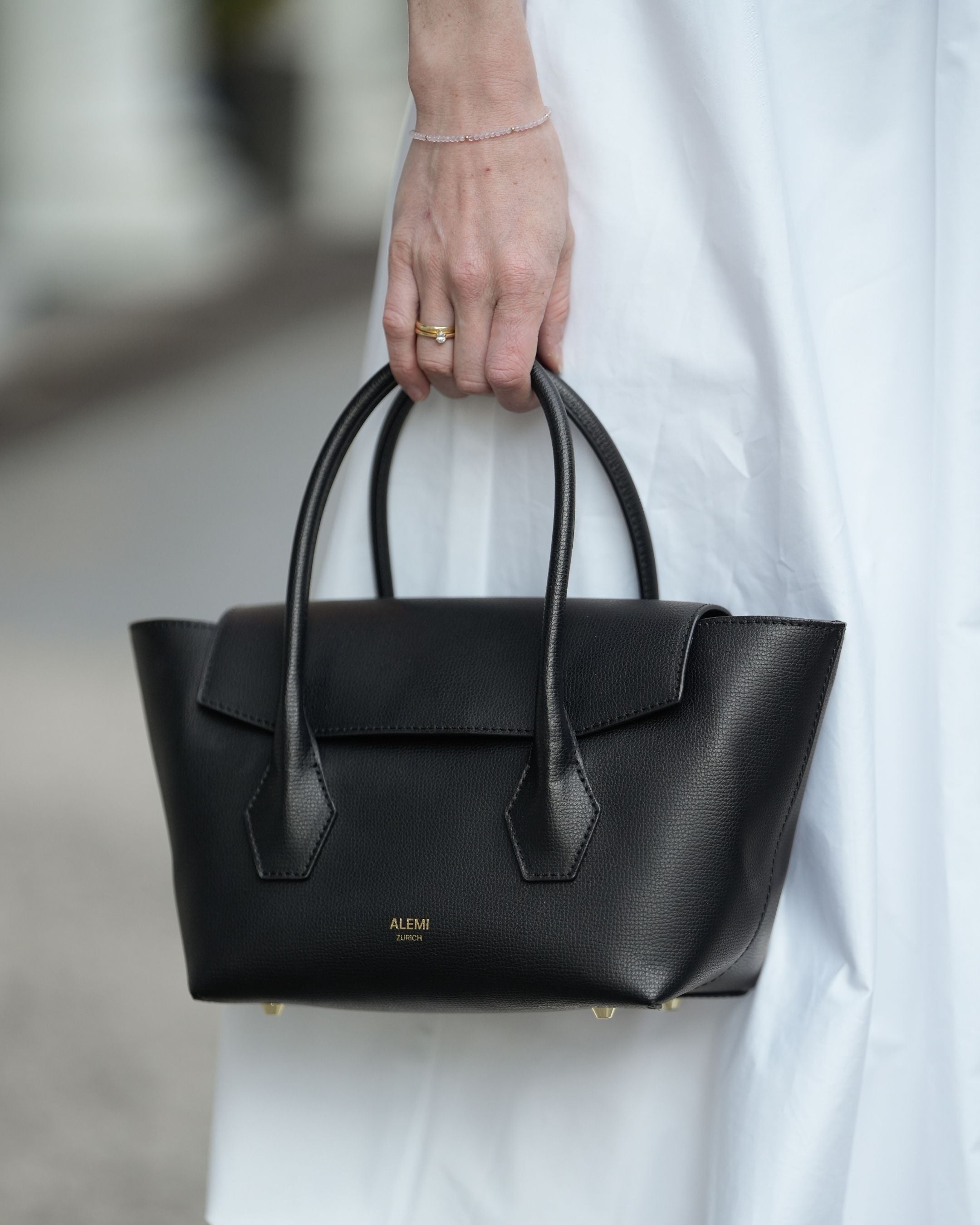 ALEMI Zurich | IDA SMALL | Small Bag | Black | Pebbled Leather | Model carrying bag by handle close up