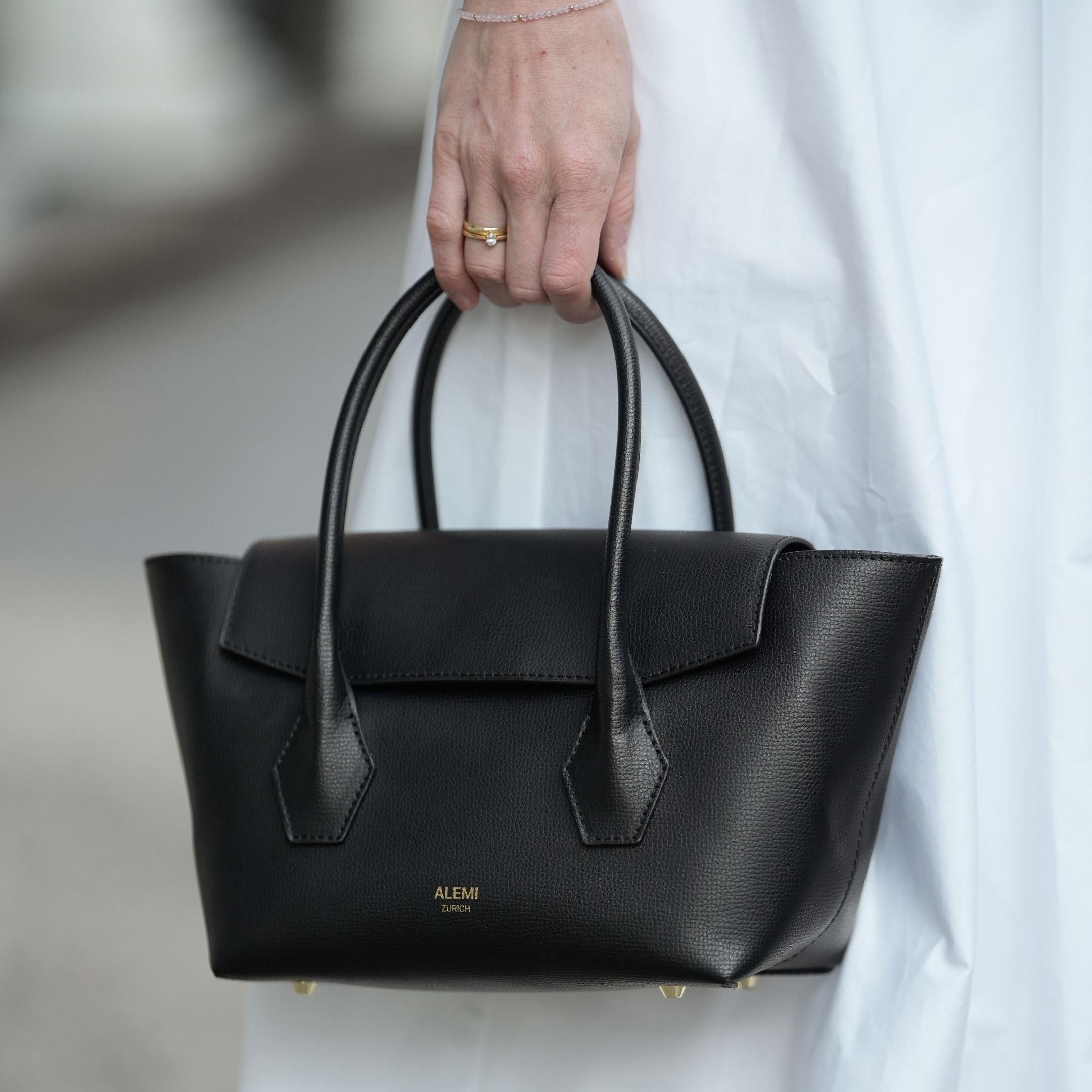 ALEMI Zurich | IDA SMALL | Small Bag | Black | Pebbled Leather | Model carrying bag by handle close up