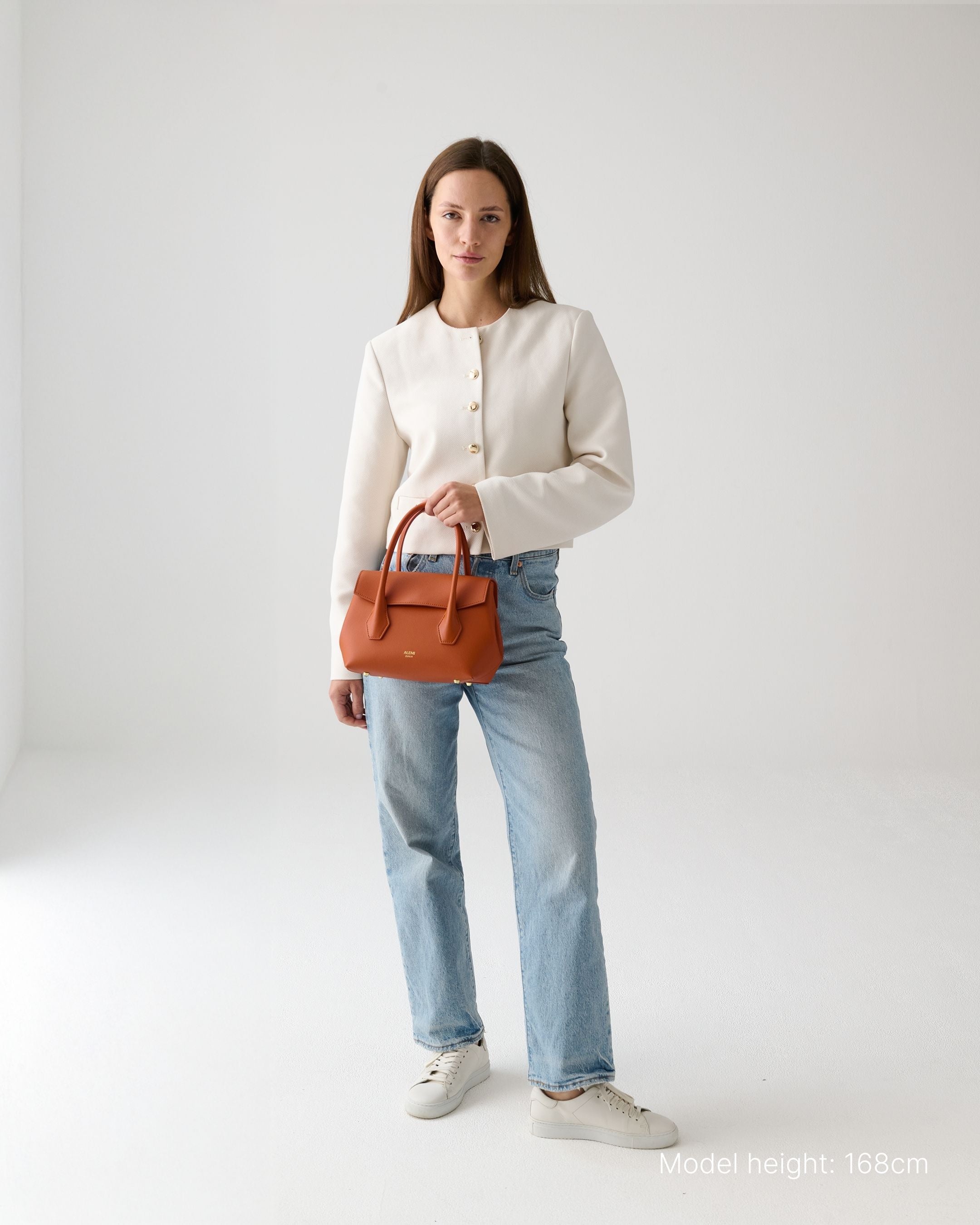 ALEMI Zurich | IDA SMALL | Small Bag | Deep Orange | Pebbled Leather | Model carrying bag by handle