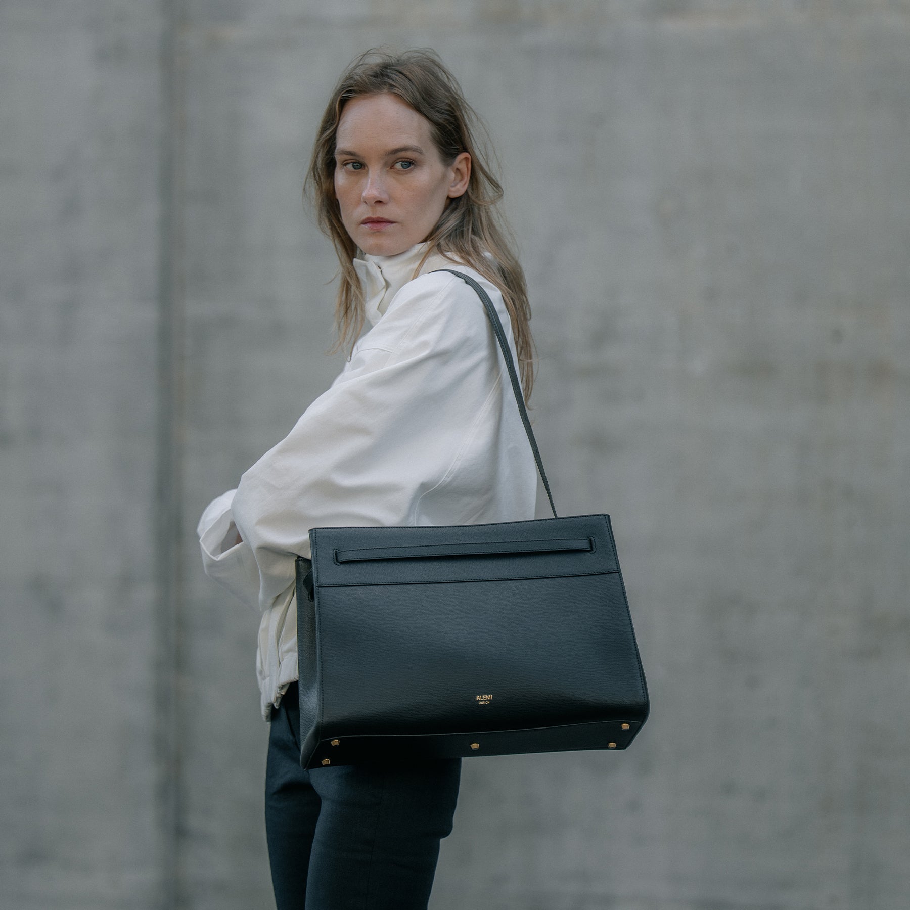 ALEMI Zurich | SEEFELD | Laptop Bag | Black | Pebbled Leather | Model carrying bag on shoulder