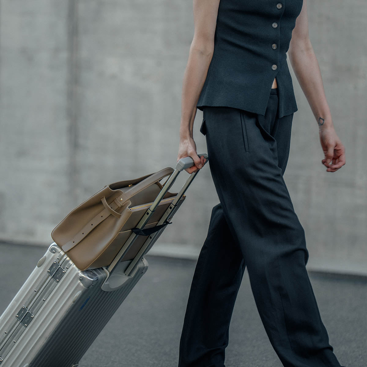 ALEMI SEEFELD bag attached to a suitcase handle with the hidden trolley strap