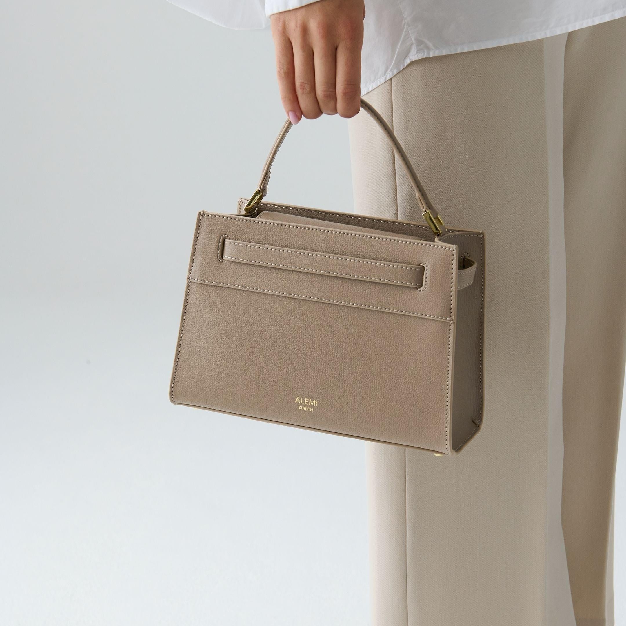 ALEMI Zurich | SEEFELD MINI | Small Bag | Greige | Pebbled Leather | Model carrying bag by handle close up