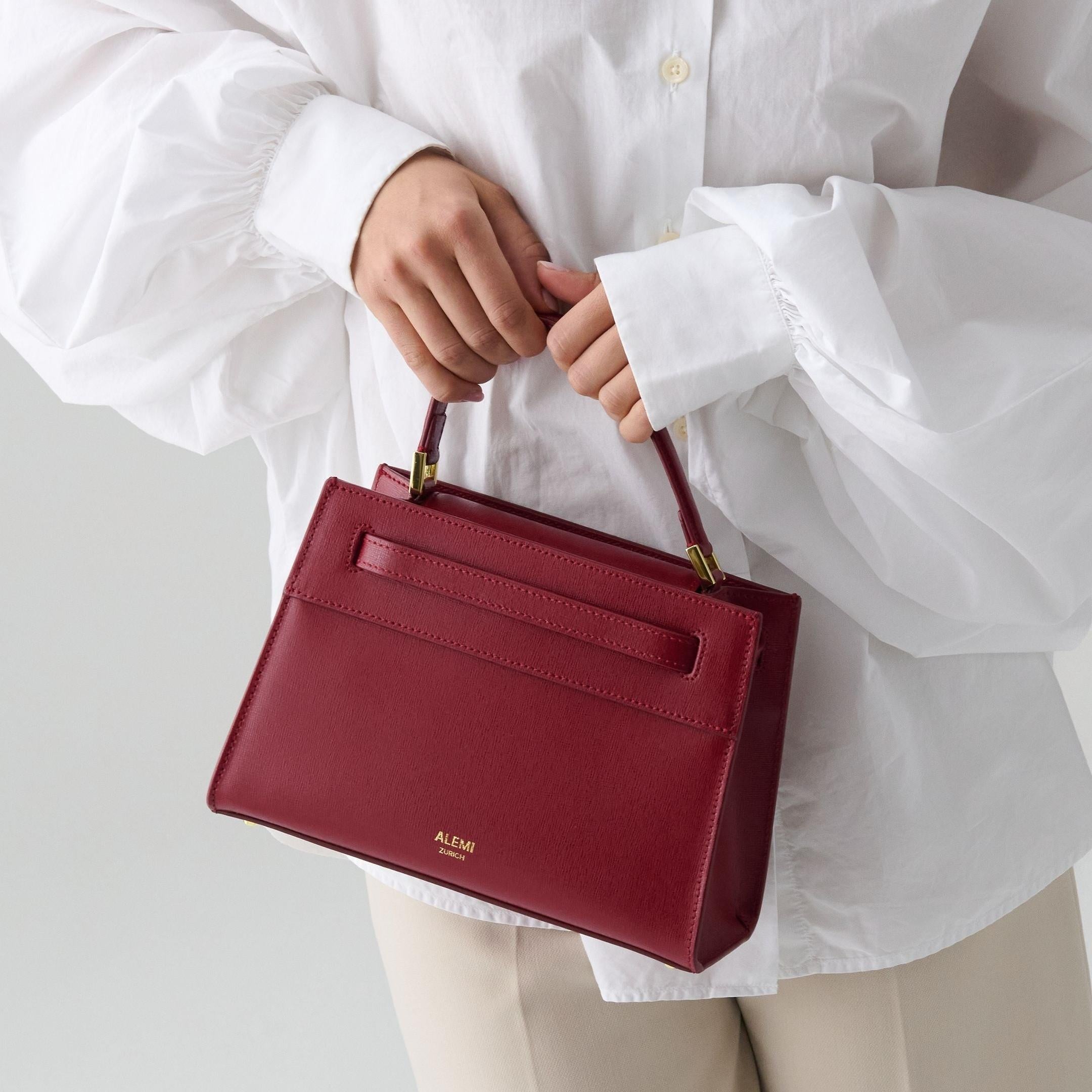 ALEMI Zurich | SEEFELD MINI | Small Bag | Red | Saffiano Leather | Model carrying bag by handle close up