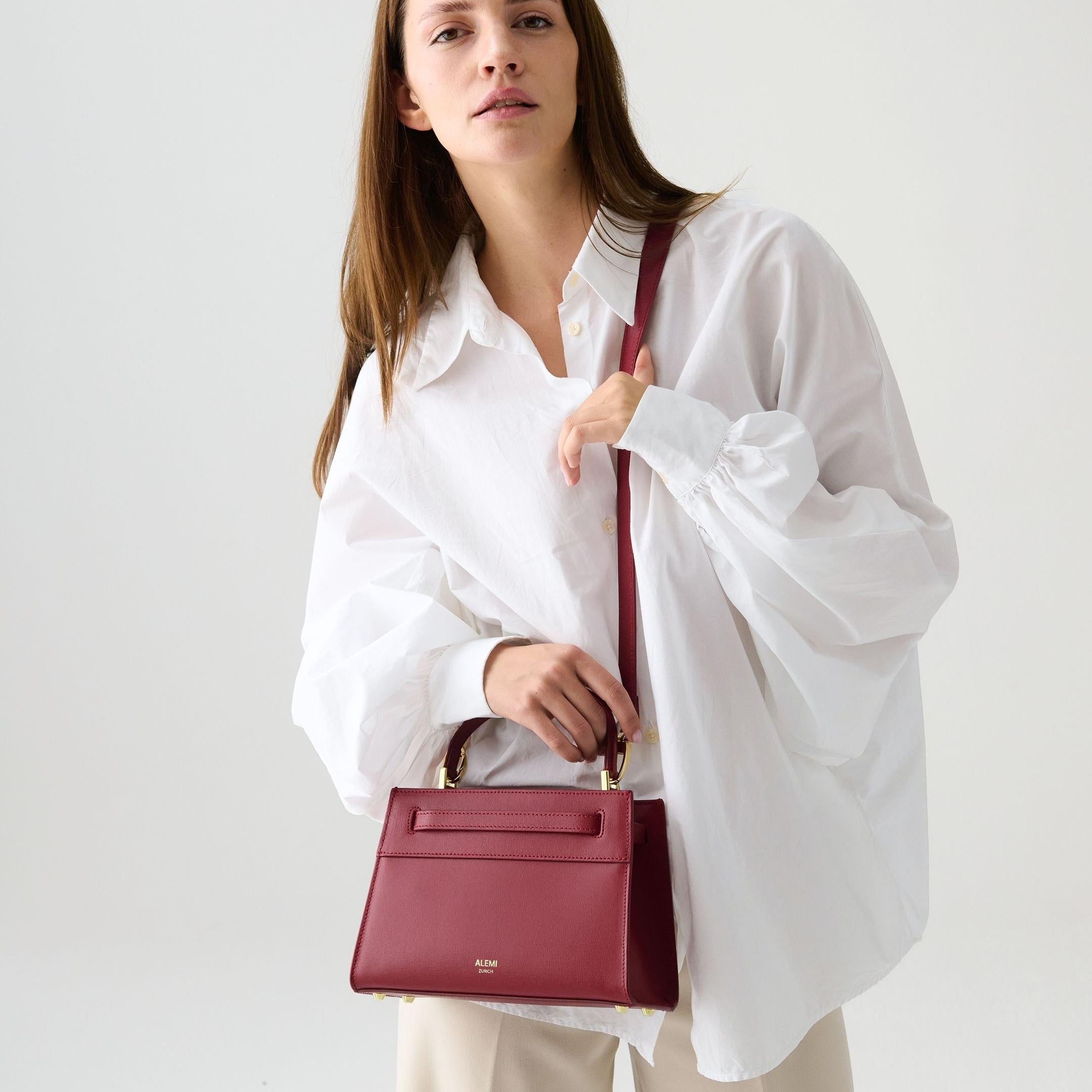 ALEMI Zurich | SEEFELD MINI | Small Bag | Red | Saffiano Leather | Model carrying bag by handle