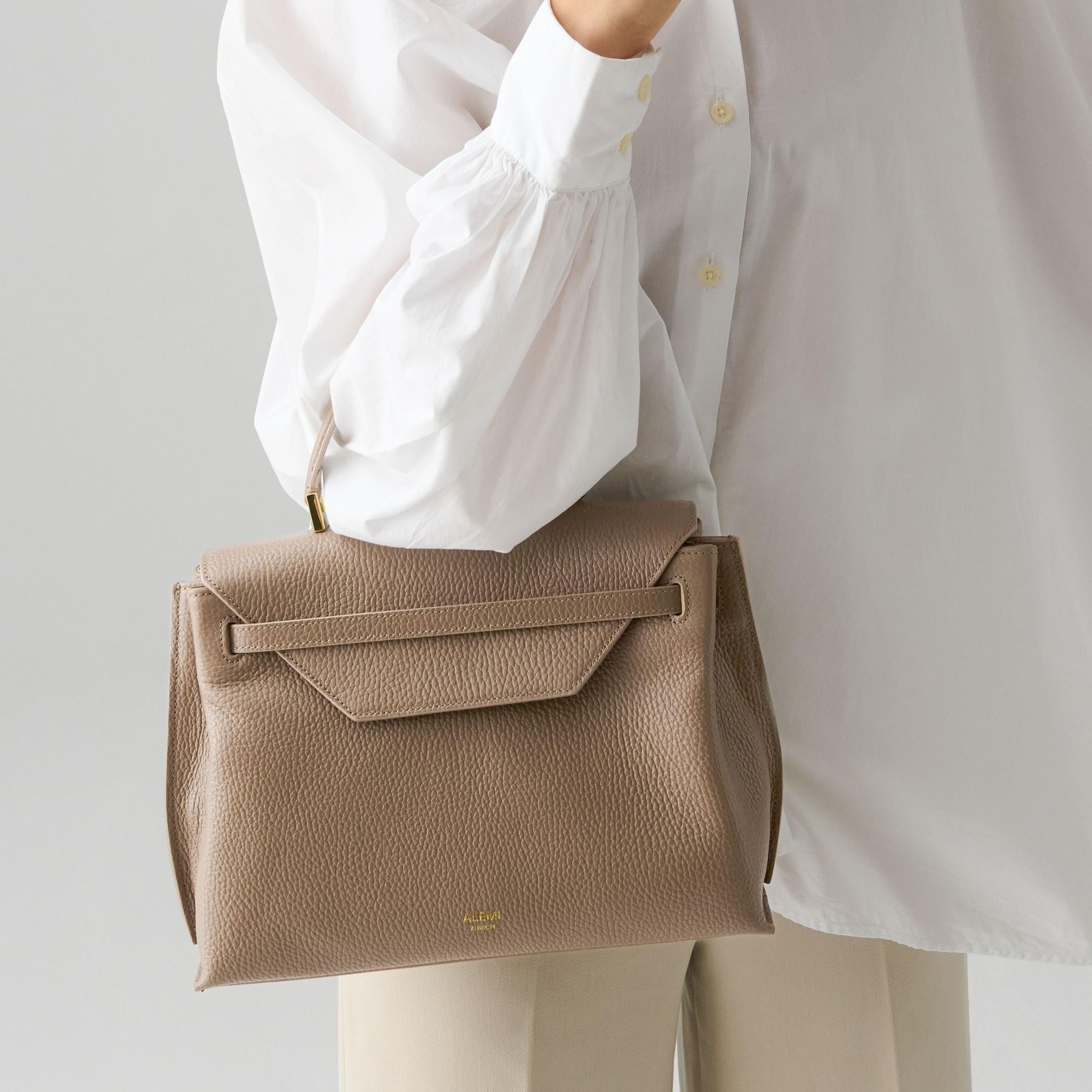 ALEMI Zurich | VIADUKT | Small Bag | Greige | Soft Grain Leather | Model carrying bag by handle