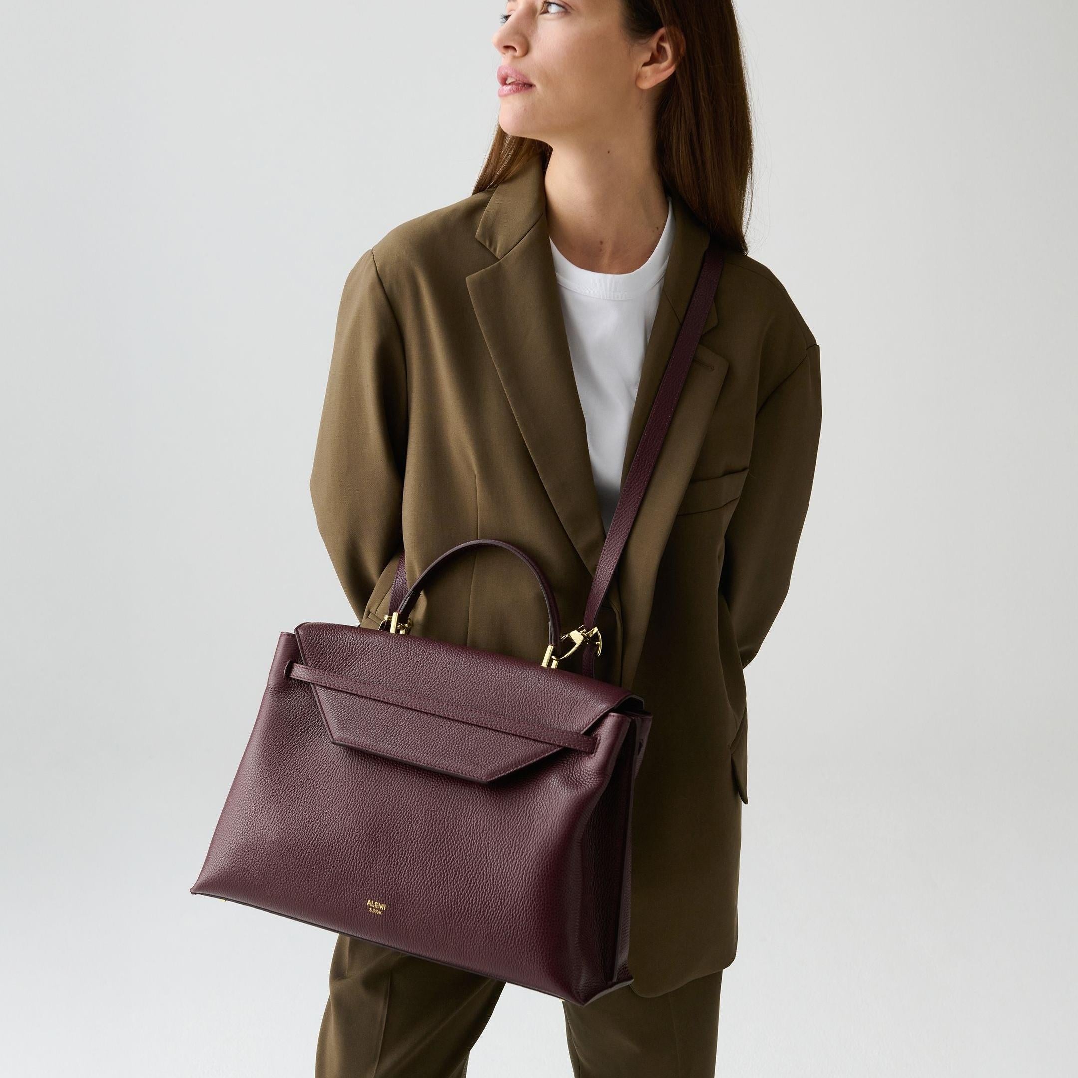 ALEMI Zurich | VIADUKT WORK | Laptop Bag | Maroon Red | Soft Grain Leather | Model carrying bag by strap