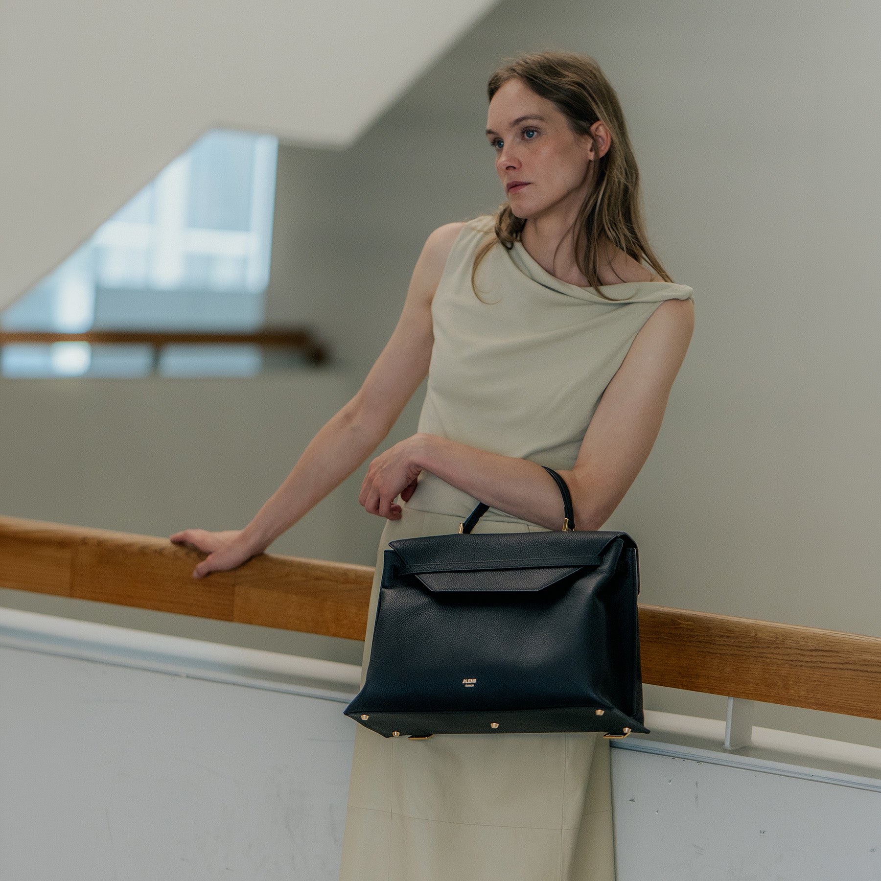 ALEMI Zurich | VIADUKT WORK | Laptop Bag | Black | Soft Grain Leather | Model holding bag by handle