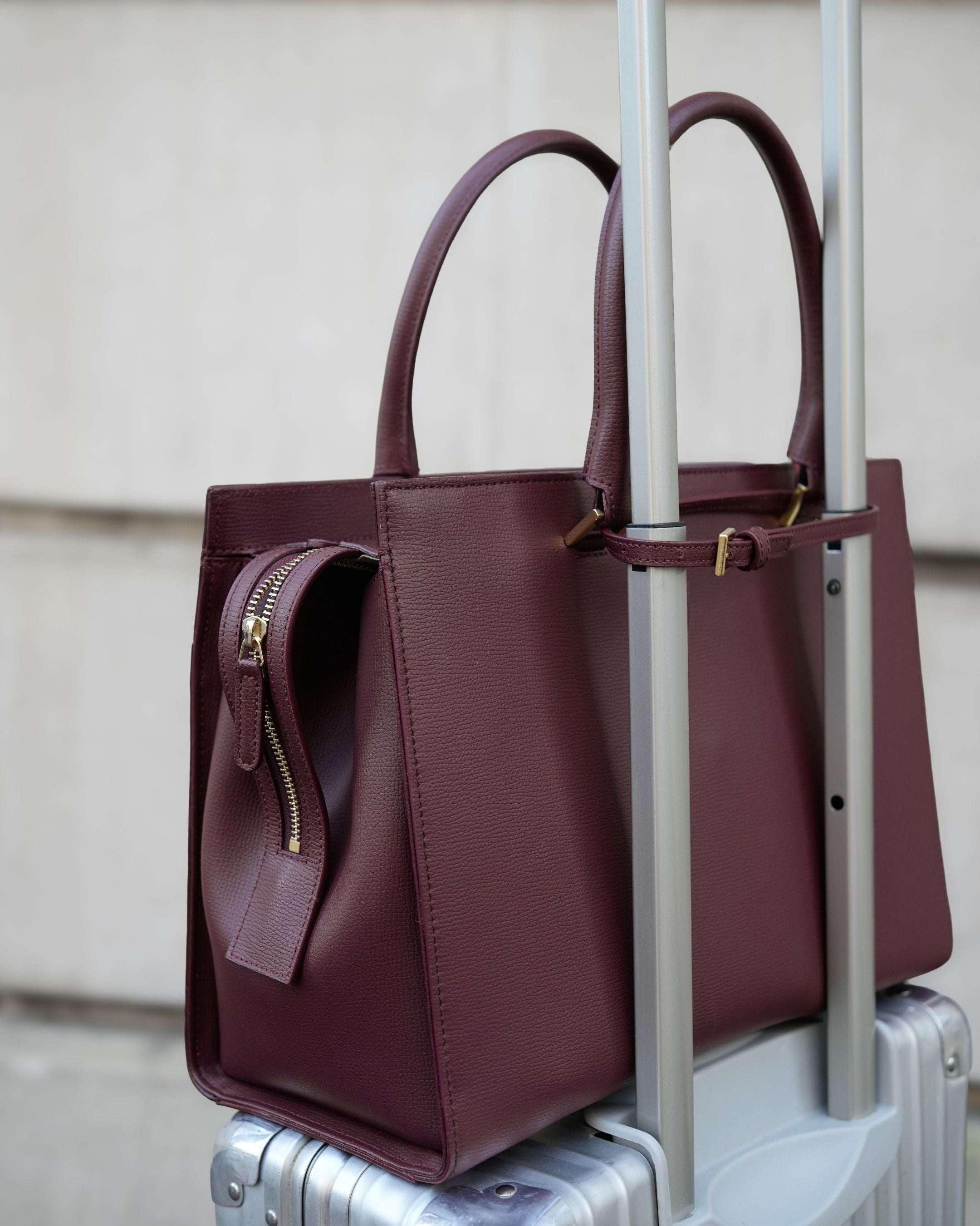 ALEMI Zurich | CENTRAL | Laptop Bag | Maroon Red | Pebbled Leather | Bag on suitcase