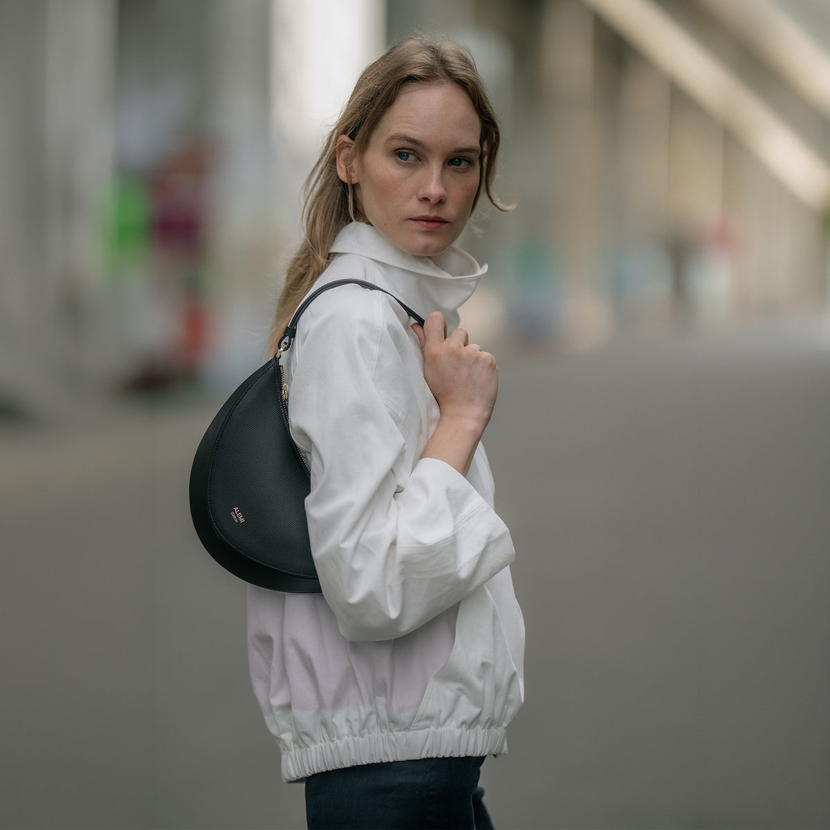 ALEMI Zurich | HELVETIA | Small Bag | Black | Pebbled Leather | Model walking with bag on shoulder