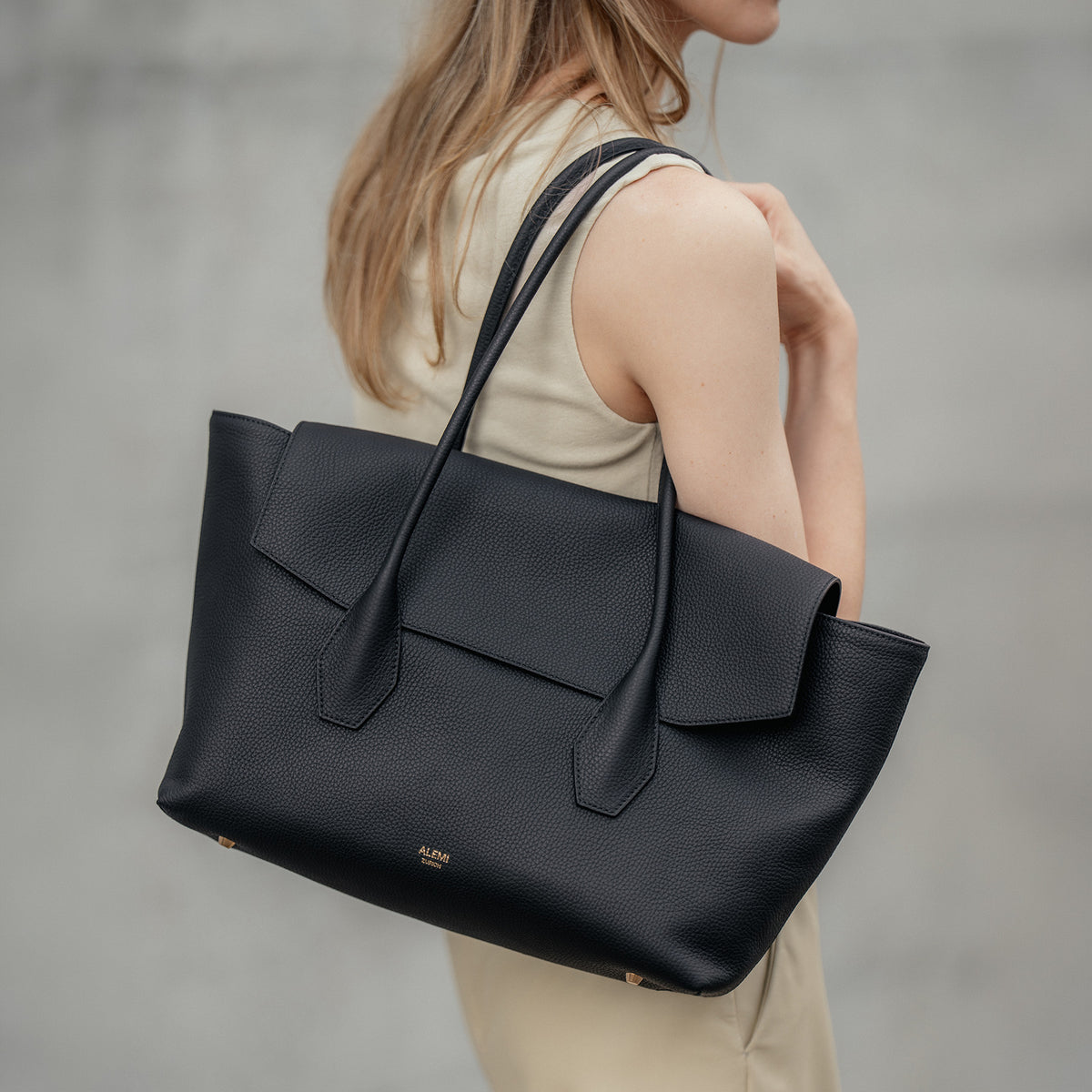 ALEMI Zurich | IDA | Laptop Bag | Black | Soft Grain Leather | Model carrying bag by top handle on shoulder