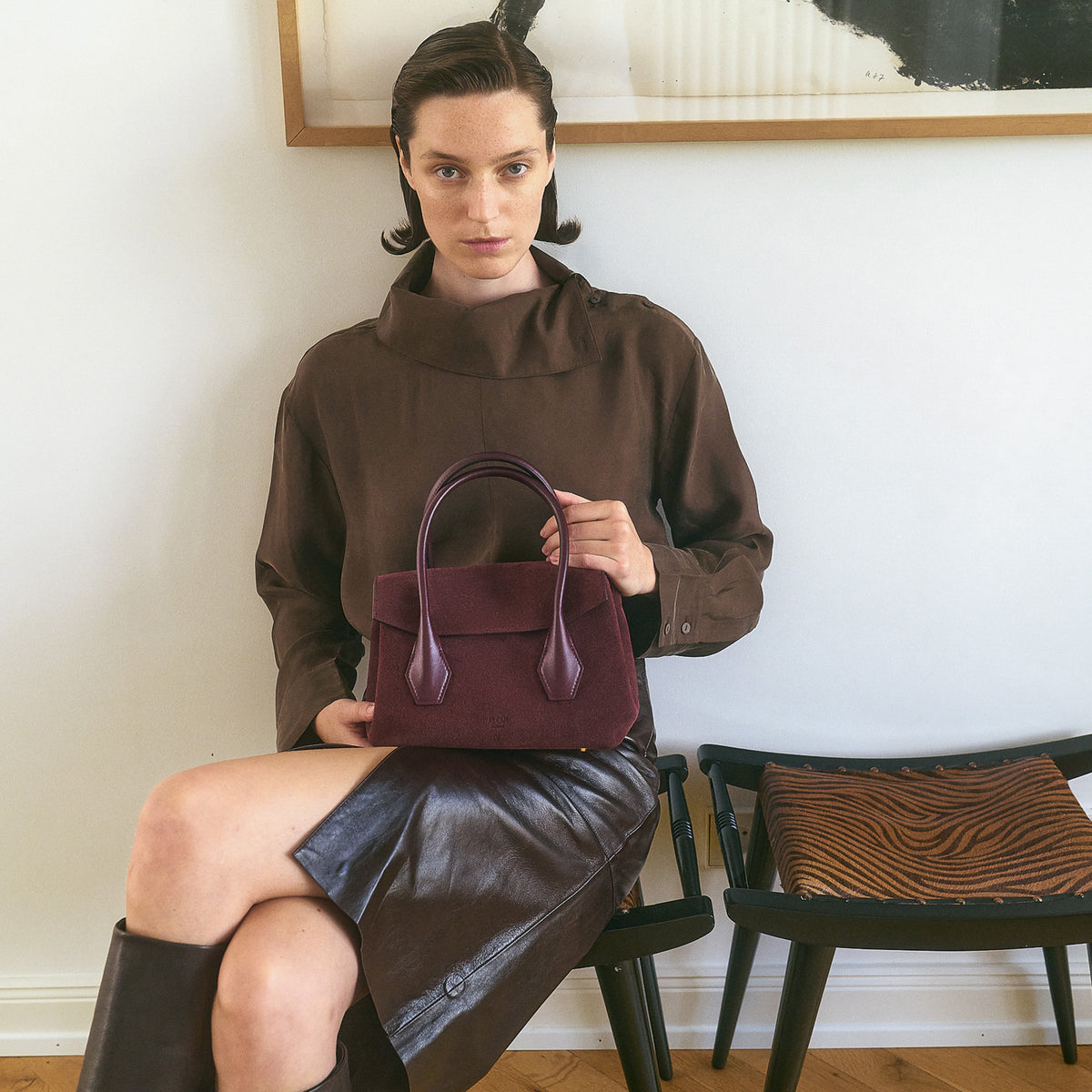 ALEMI Zurich | IDA SMALL | Small Bag | Maroon Red | Suede Leather | Model seated holding bag on lap
