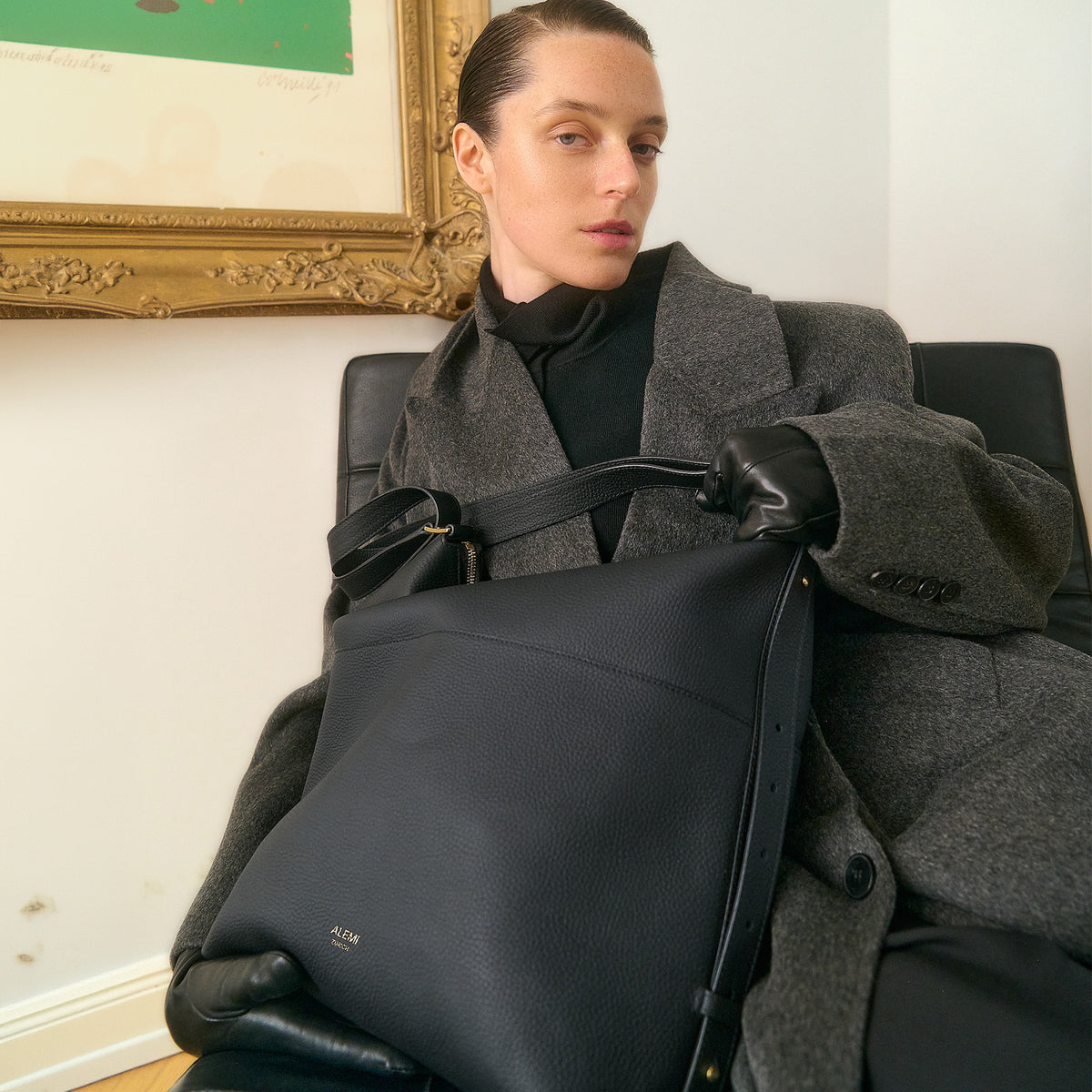 ALEMI Zurich | LETTEN | Laptop Bag | Black | Soft Grain Leather | Model seated holding bag on lap