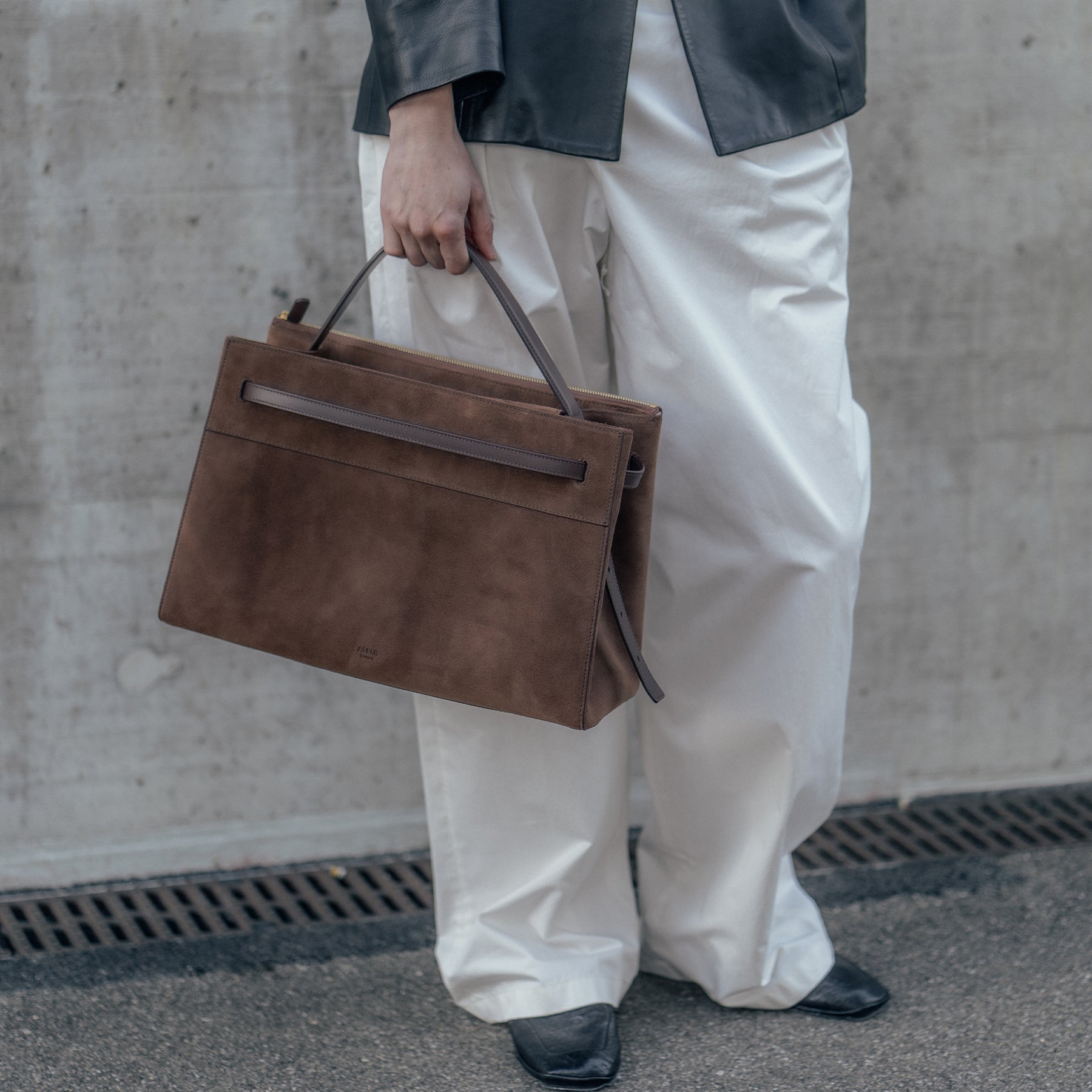 ALEMI Zurich | SEEFELD | Laptop Bag | Dark Brown | Suede Leather | Model carrying bag by handle