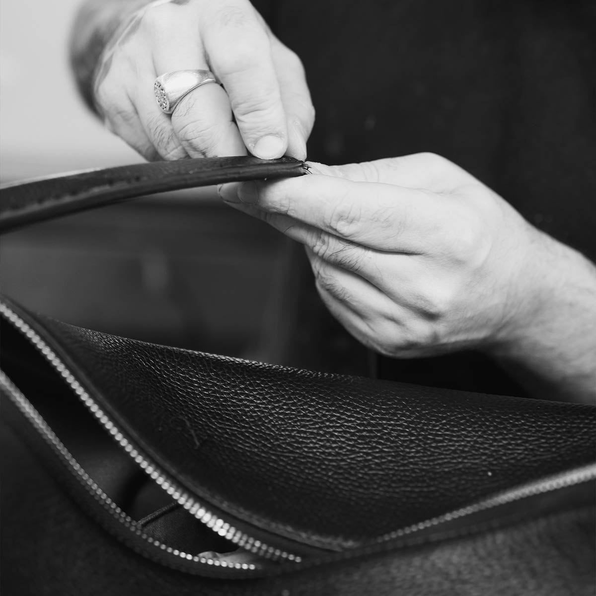 Craftsman finishing the edge of an Italian leather bag by hand