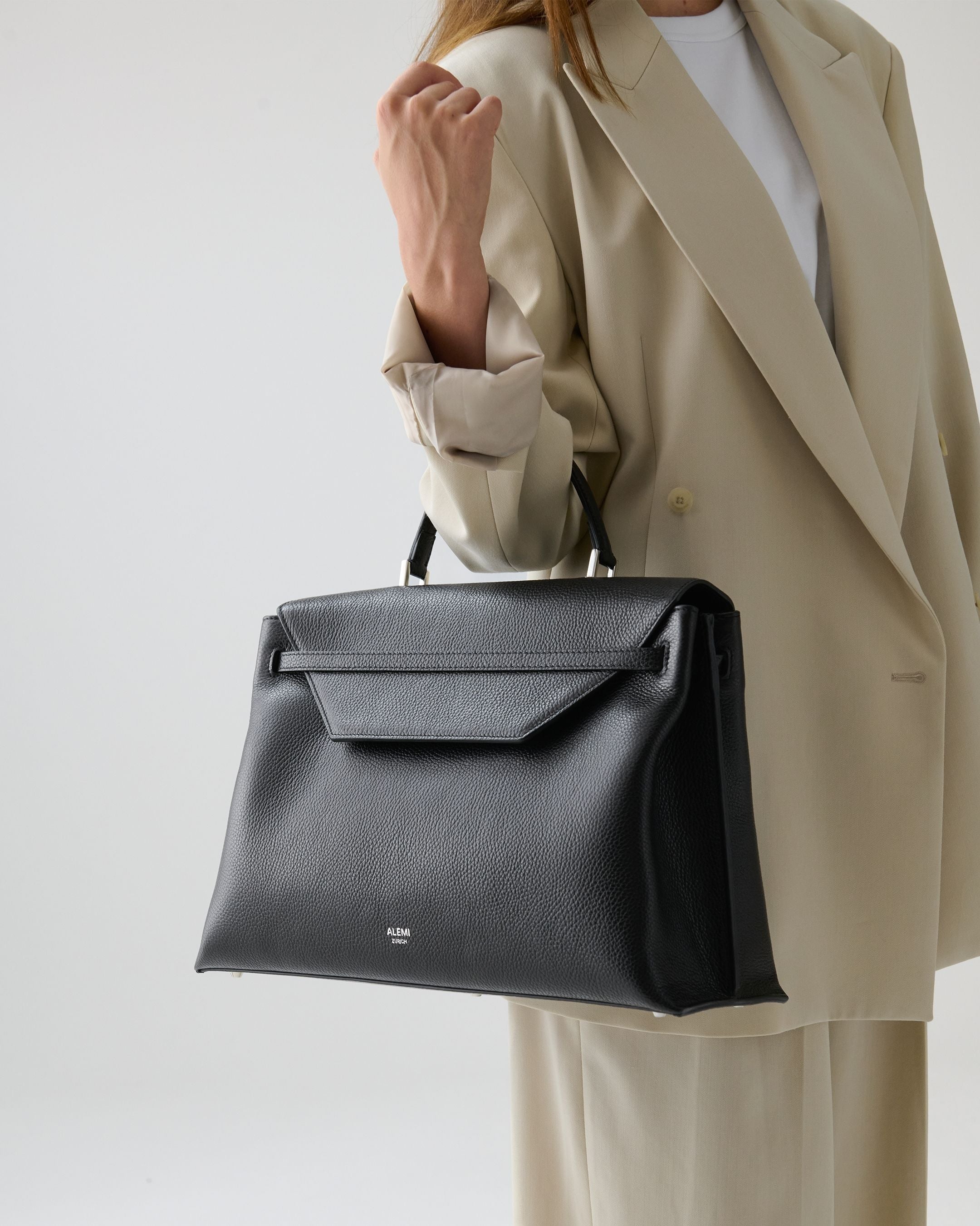 ALEMI Zurich | VIADUKT WORK | Laptop Bag | Black with Silver Hardware | Soft Grain Leather | Model carrying bag by handle-close-up
